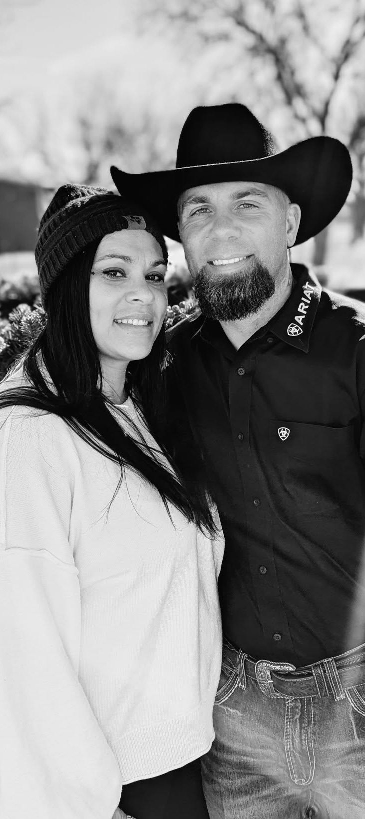 Kenneth Krickbaum, in a black hat and shirt, smiling beside his wife outdoors.